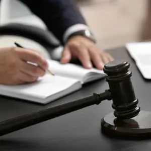 Advogado analisando um contrato jurídico com um martelo de juiz ao lado, representando negócios jurídicos e falhas na prestação de serviços.