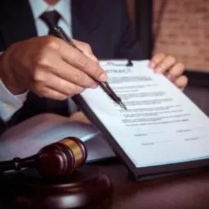 Pessoa assinando um documento legal, representando ações de responsabilidade civil, indenizações e uso indevido de imagem.
