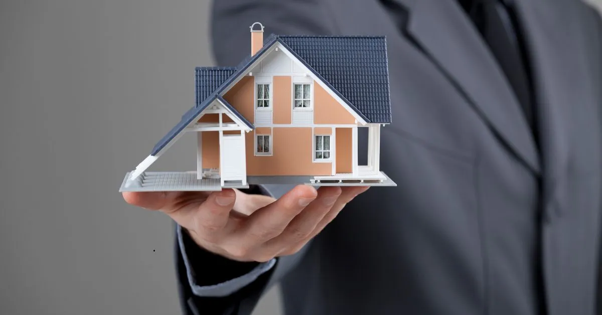Homem de terno segurando maquete de casa simbolizando benfeitorias no aluguel e direito a indenização