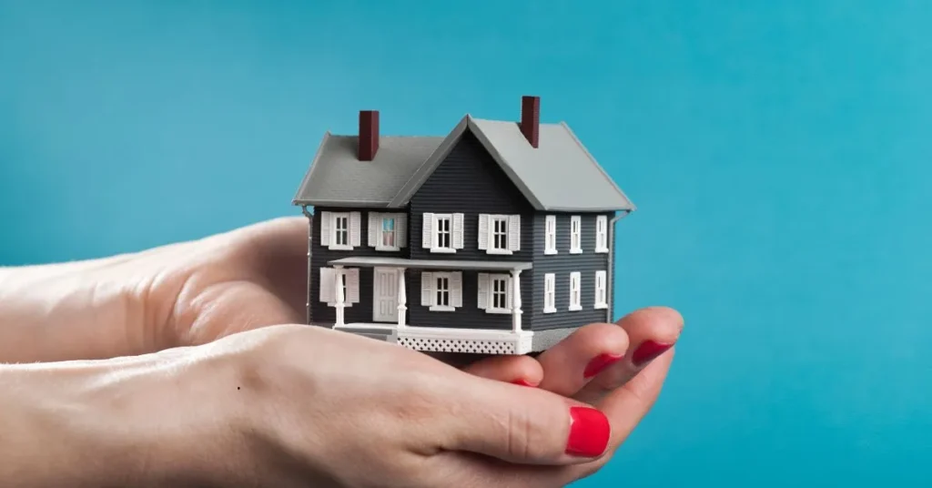 Casa em miniatura sustentada por mãos femininas, representando segurança na usucapião extrajudicial