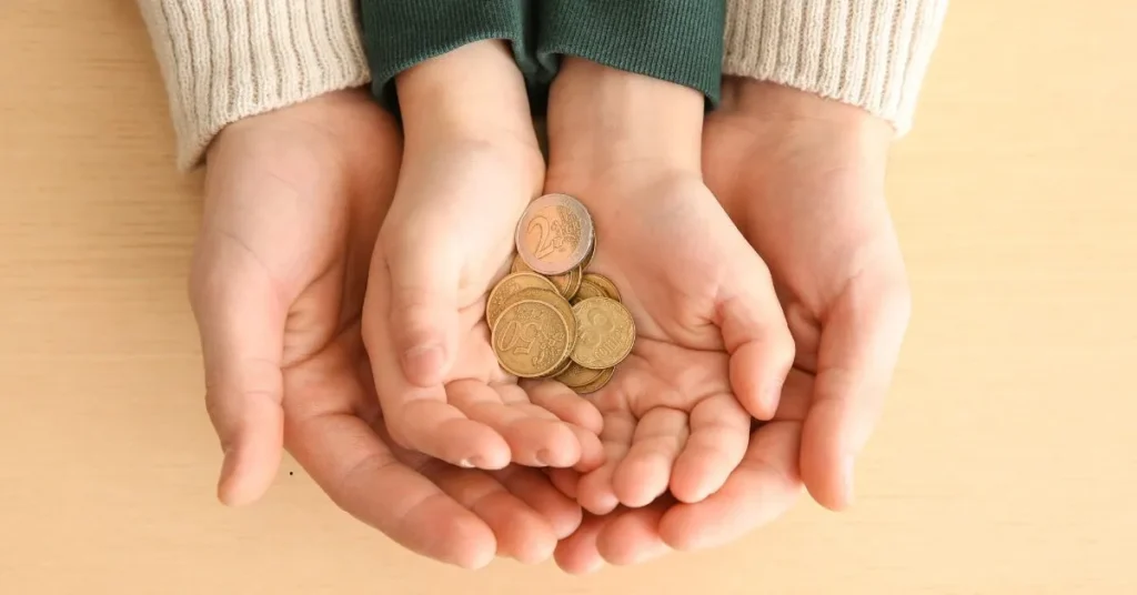 Pensão alimentícia: mãos de adulto seguram mãos de criança com moedas, simbolizando sustento compartilhado