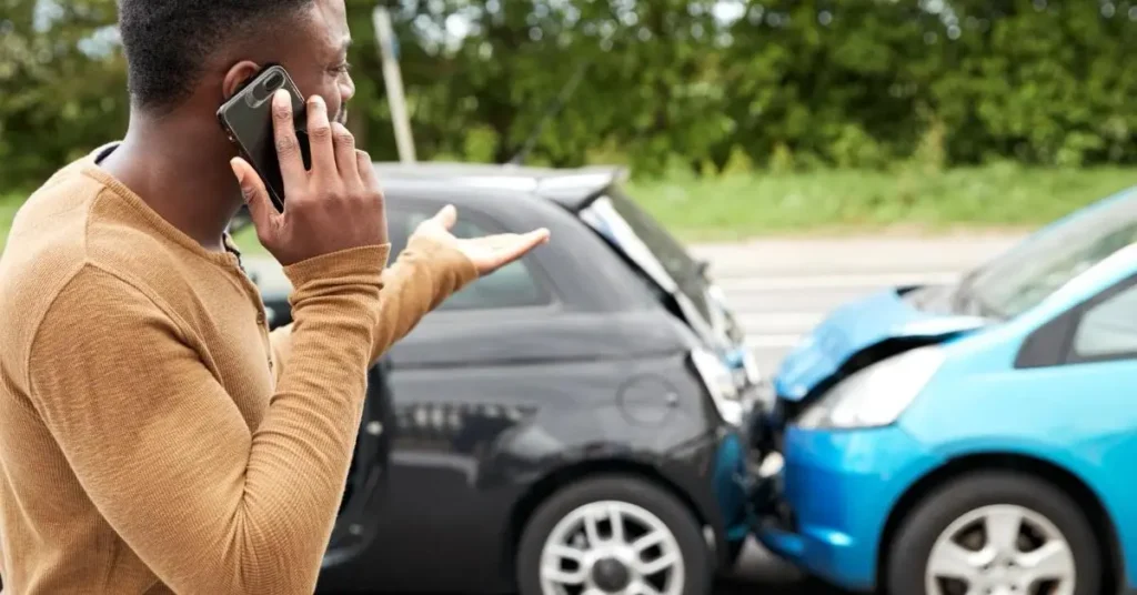 Motorista ao telefone diante de colisão entre dois carros, ilustrando indenização por acidente de trânsito segundo o Código Civil