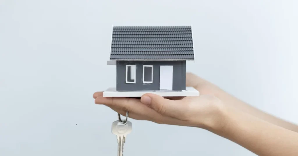 Mãos segurando maquete de casa e chaves, simbolizando atraso na entrega do imóvel e pedido de indenização