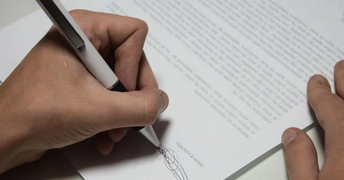 Mão assinando petição para reabilitação criminal e limpeza de antecedentes
