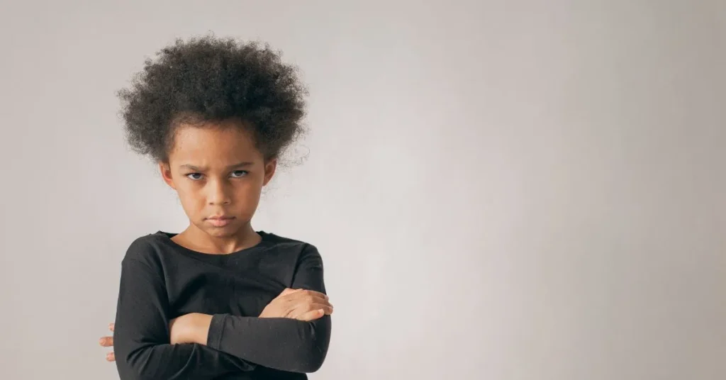 Filhos podem escolher com quem vão morar? Criança com braços cruzados e expressão séria, simbolizando conflitos de guarda e convivência