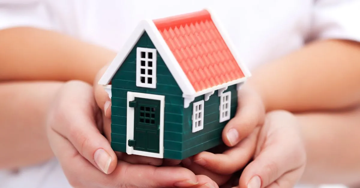 Mãos segurando uma casa em miniatura, simbolizando imóvel alugado e venda pelo proprietário e os direitos do inquilino.