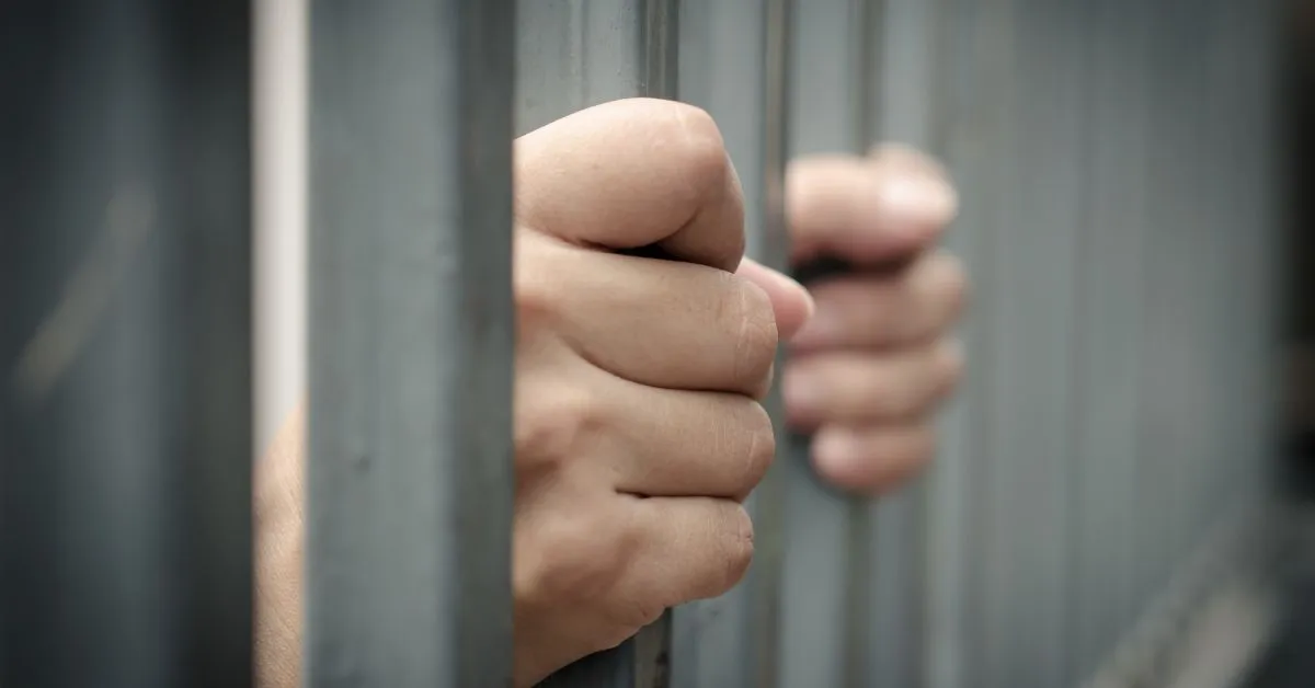 Prisão em segunda instância no Brasil representada por mãos segurando grades de cela, tema ligado à execução da pena e ao Tribunal do Júri.