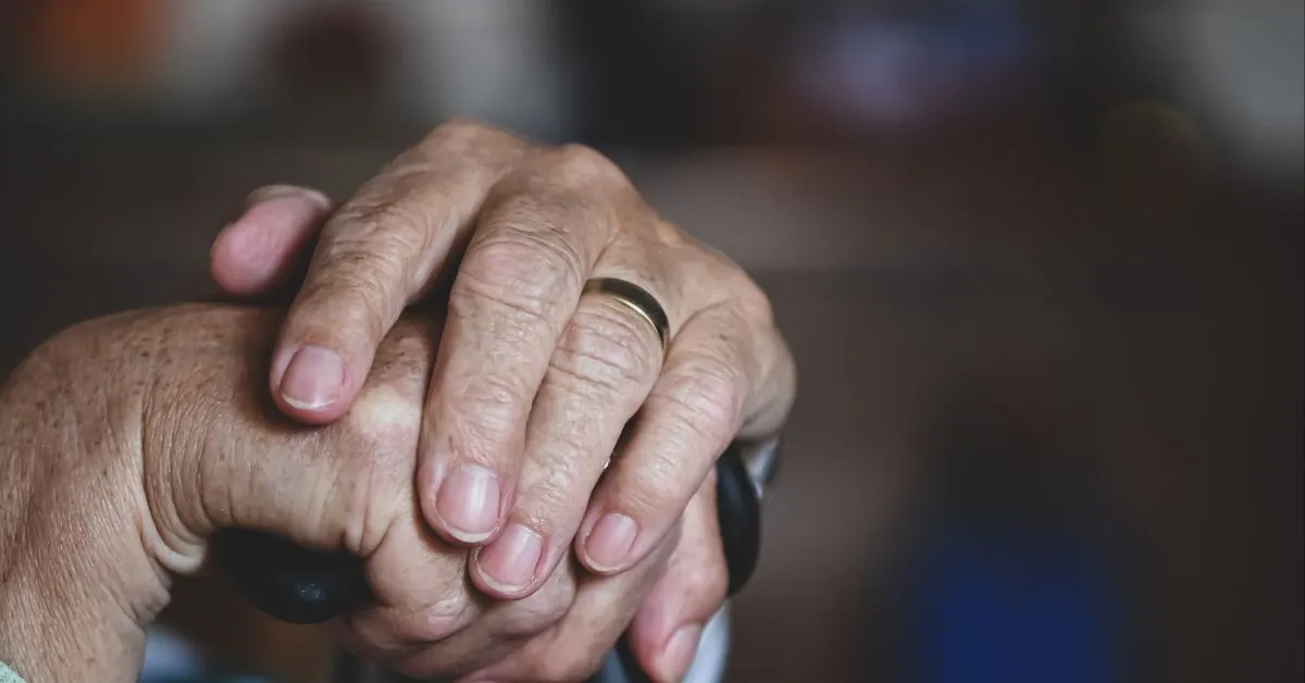 Mãos de idoso apoiadas em uma bengala simbolizando segurança e dignidade na aposentadoria híbrida somando tempo rural e urbano