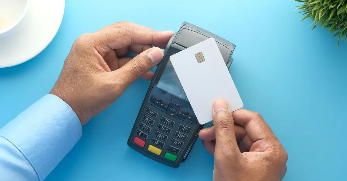Consumidor realizando pagamento com cartão e máquina de cartão, representando compra e variação de preço.