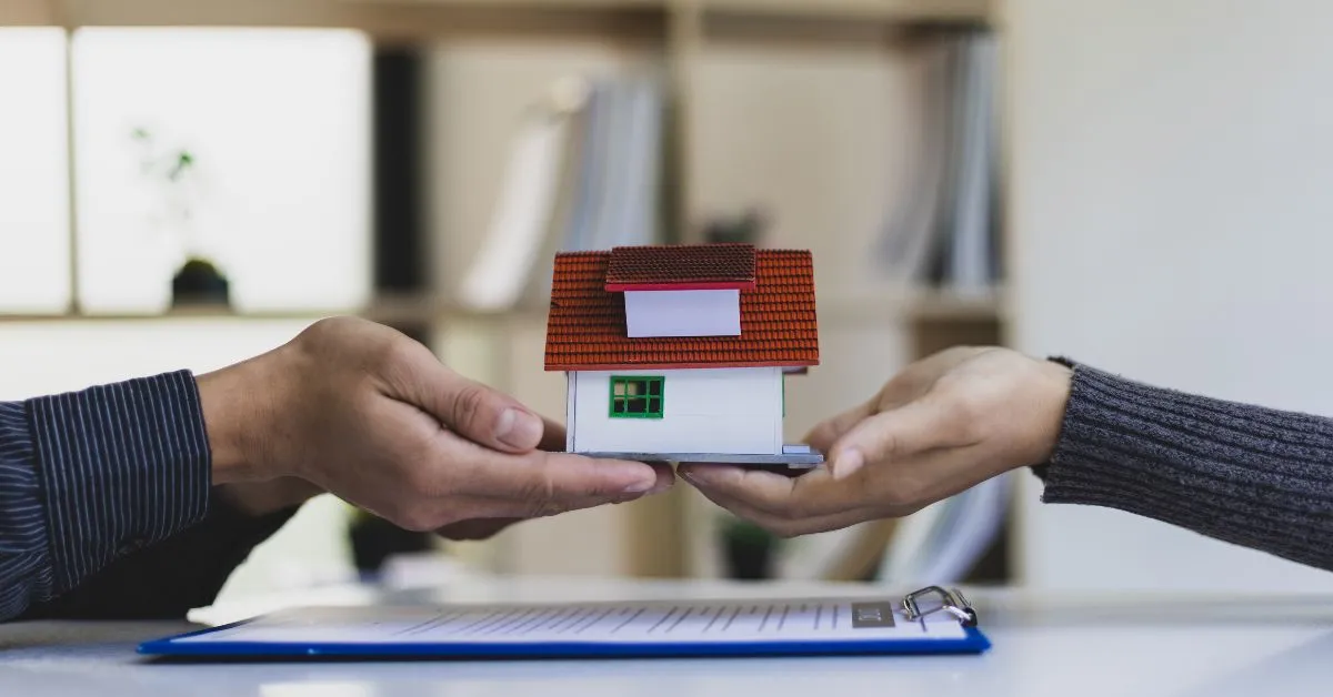 Casal segurando miniatura de casa simbolizando partilha e herança em regime de separação total de bens.