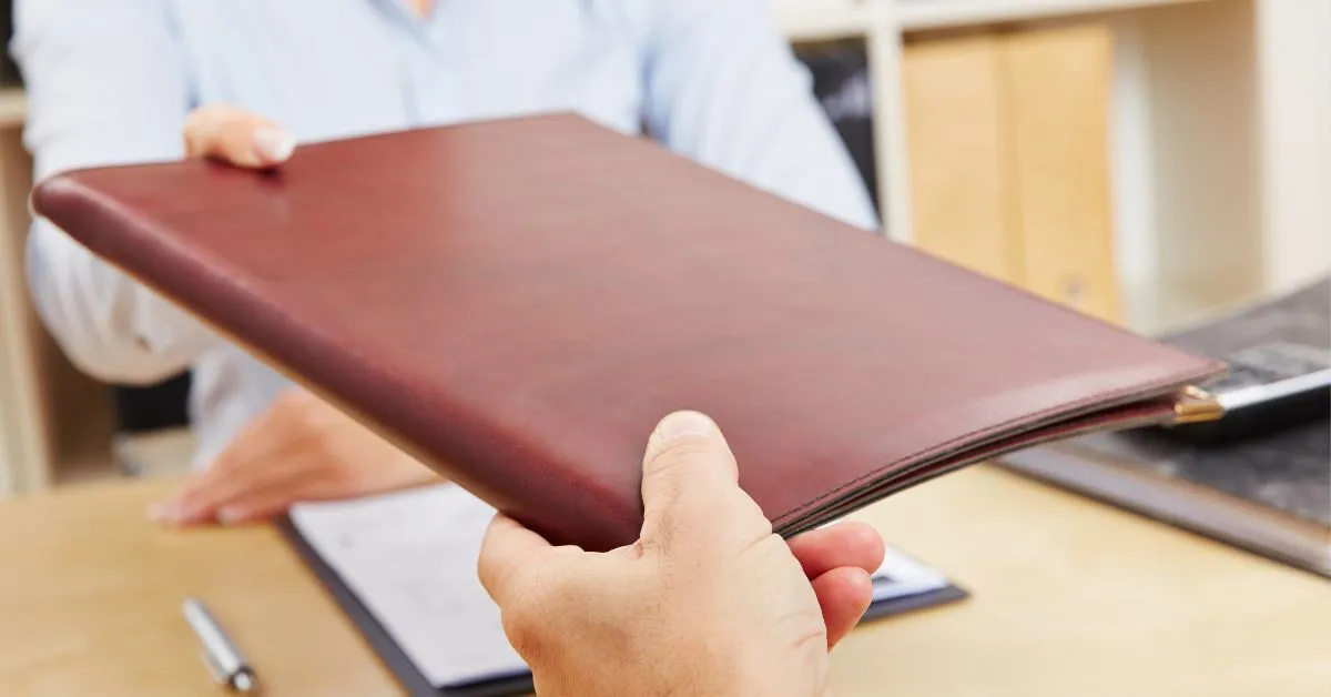 Pessoa entregando uma pasta de documentos em atendimento jurídico sobre nome negativado indevidamente.