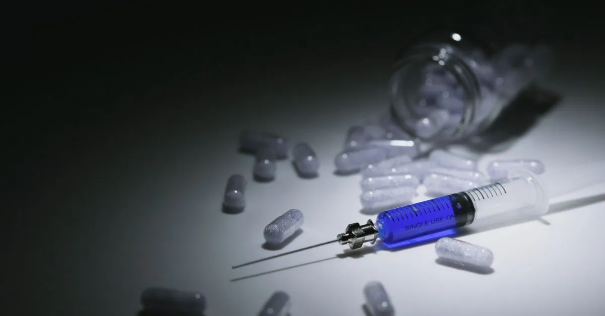 Seringa e cápsulas espalhadas simbolizando o crime de tráfico de drogas e suas consequências legais no Brasil.