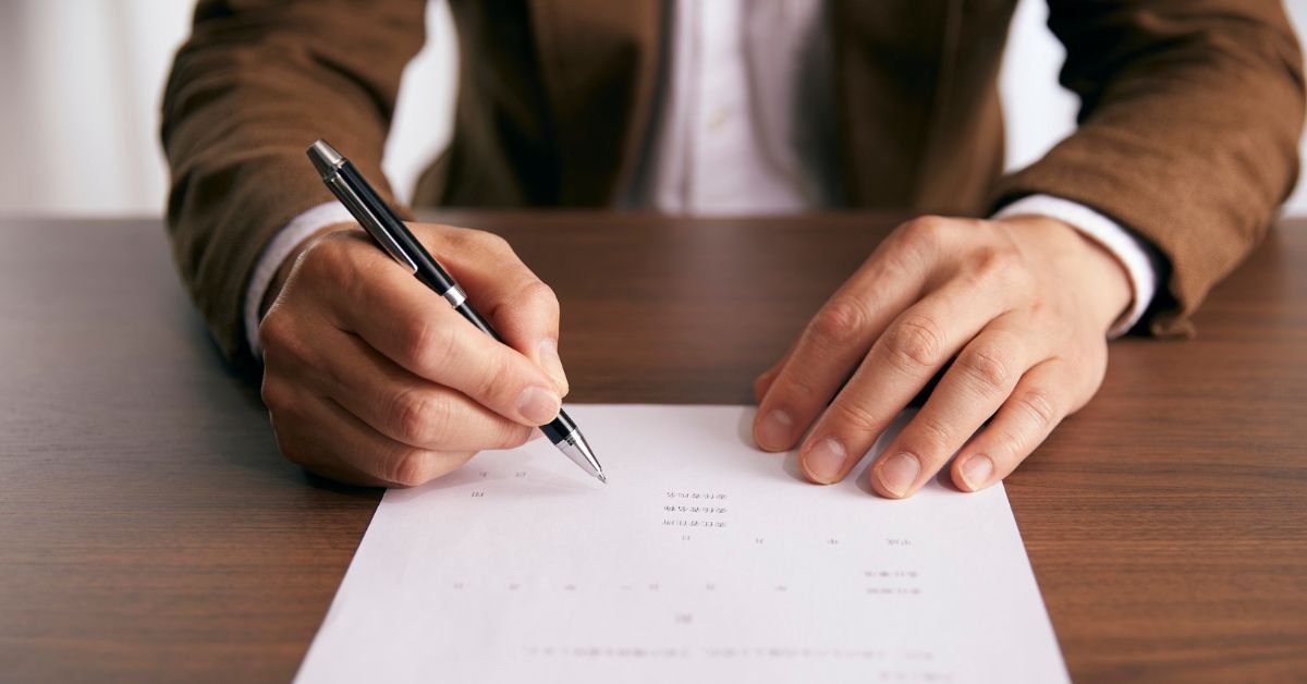 homem assinando contrato sobre mesa de madeira representando validade e nulidade contratual no direito civil