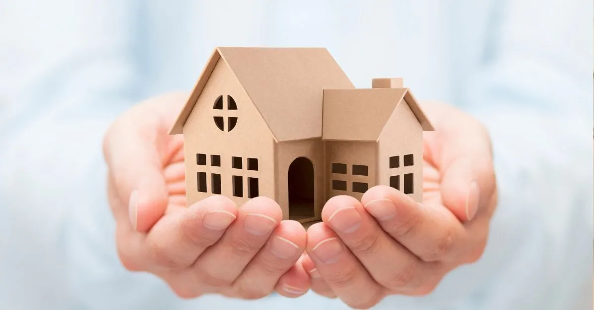 Penhora de imóvel único no nome de fiador sendo representada por mãos segurando uma casa de papelão.