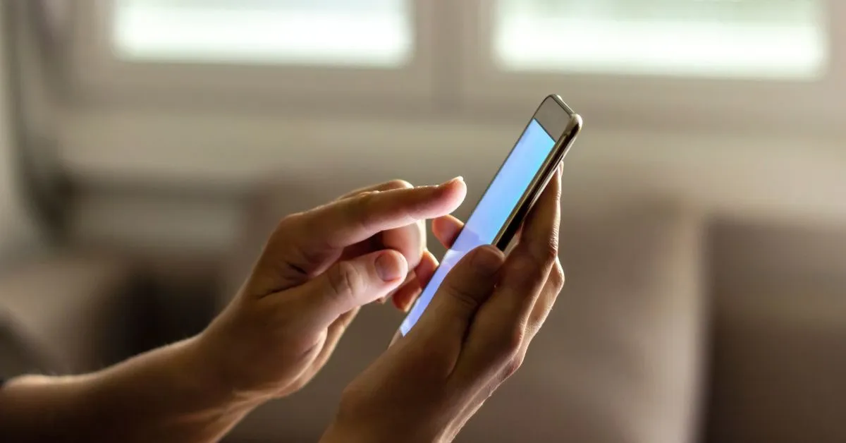 Mãos segurando um celular representando riscos de danos morais por exposição indevida de dados pessoais.