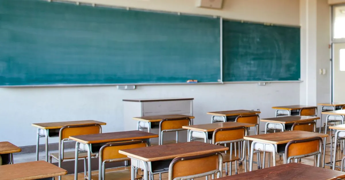 Aposentadoria de professores depois da reforma ilustrada por sala de aula vazia com quadro verde e carteiras escolares