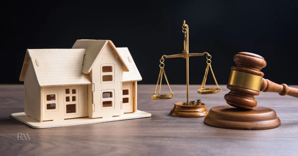 Casa em miniatura ao lado de balança da Justiça e martelo, representando a adjudicação compulsória para regularização de imóvel.
